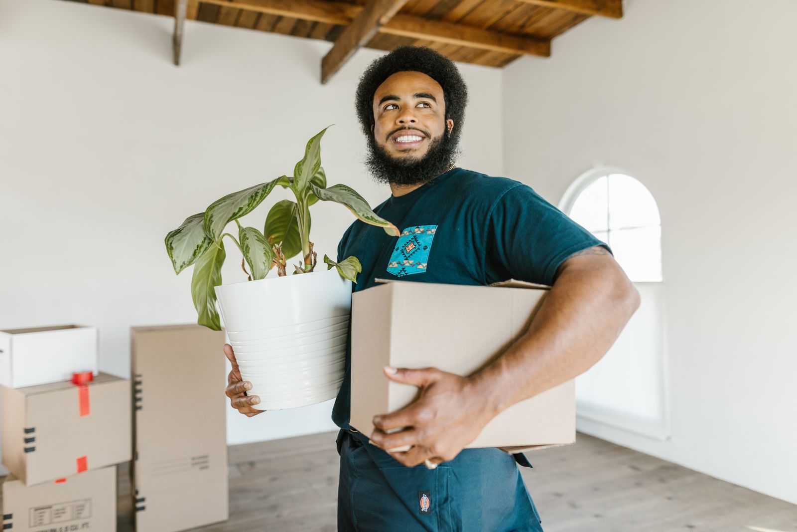A Nyati Movers crew member carrying a plant and a box into a new home