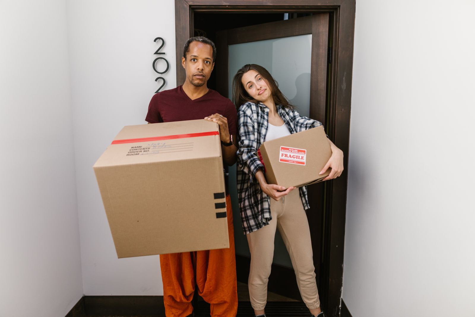 A couple carrying boxes through the door of their new apartment on moving day