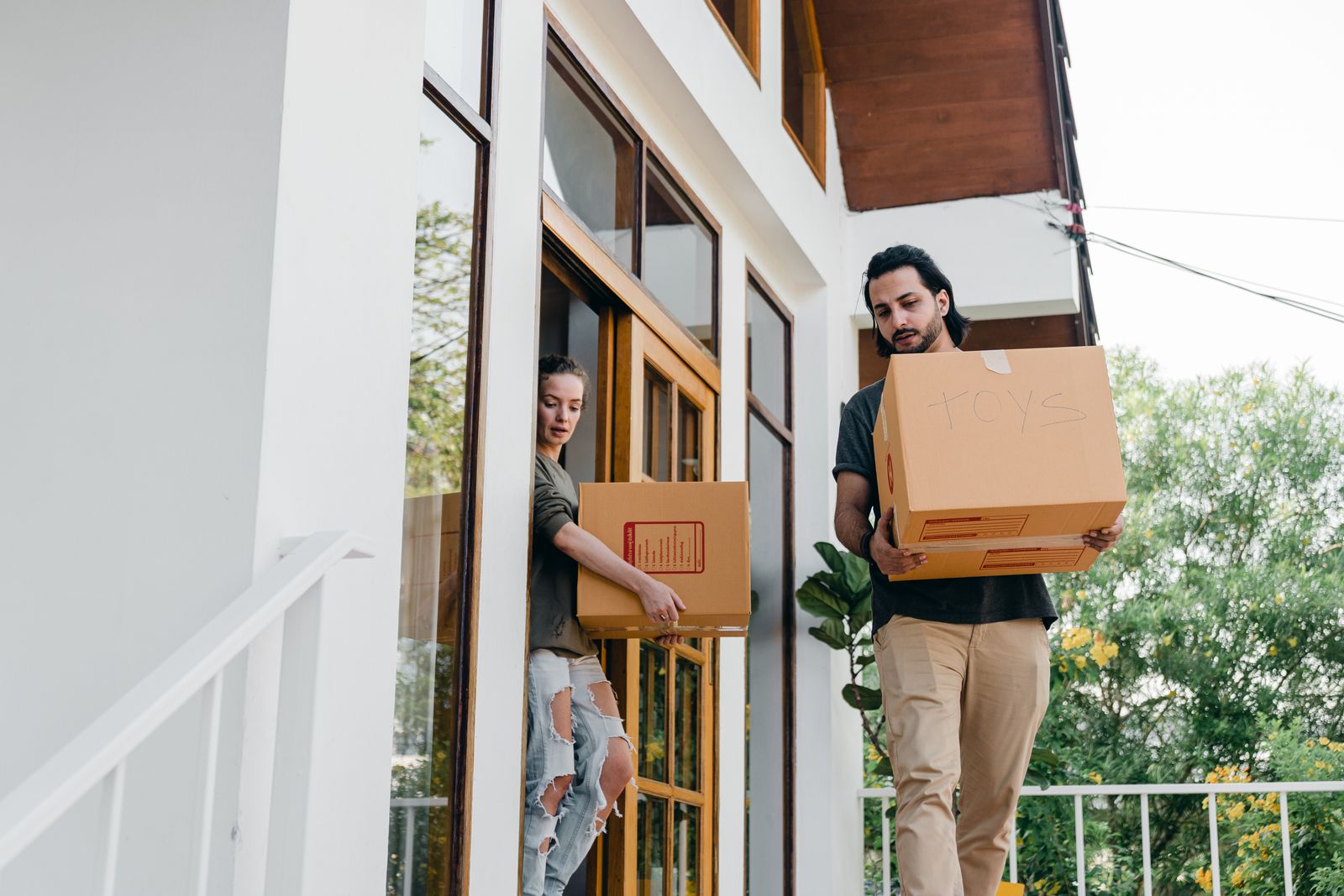 A family carrying boxes out of their old house during a move handled by Nyati Movers