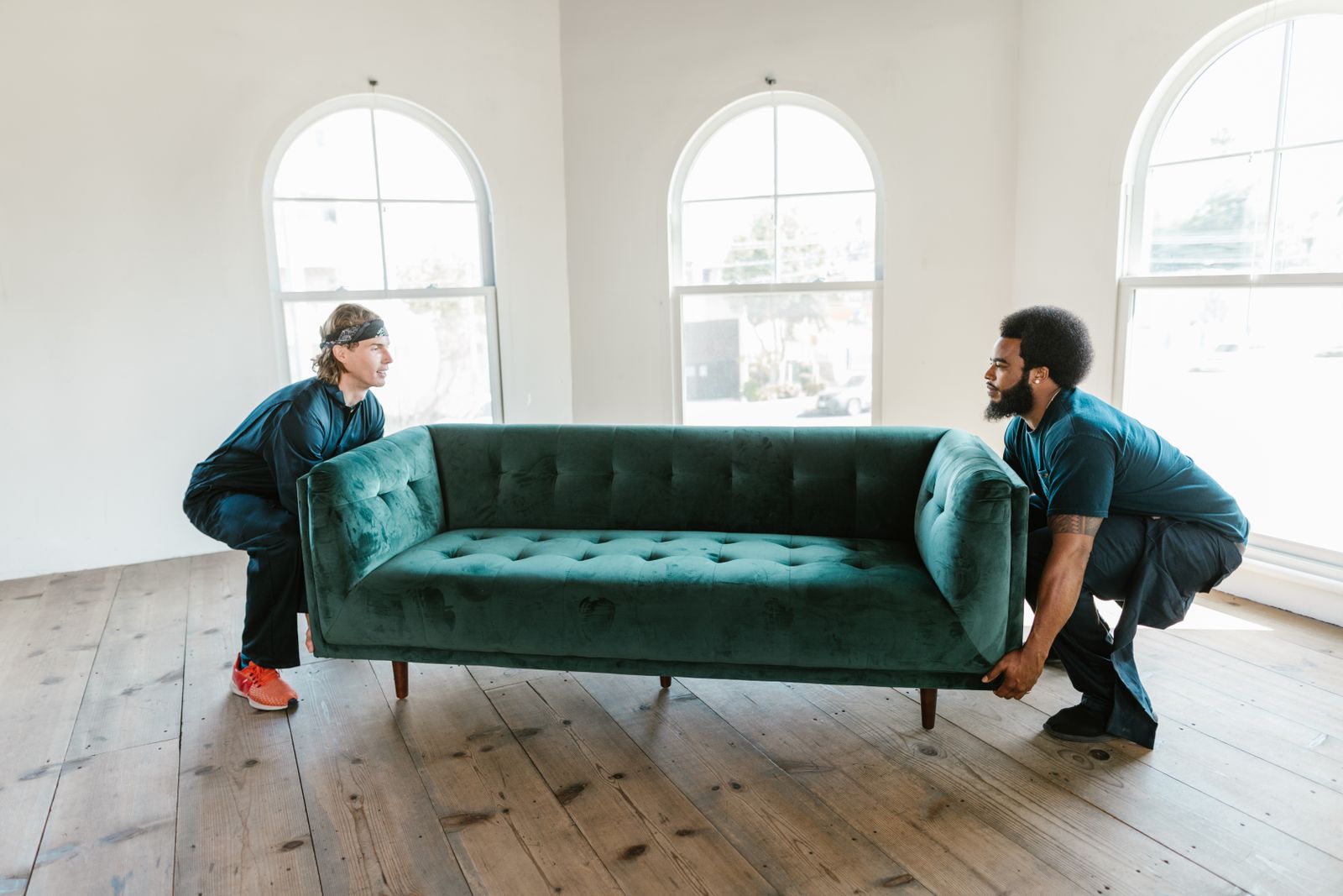 Two Nyati Movers crew members lifting a sofa together in an empty room